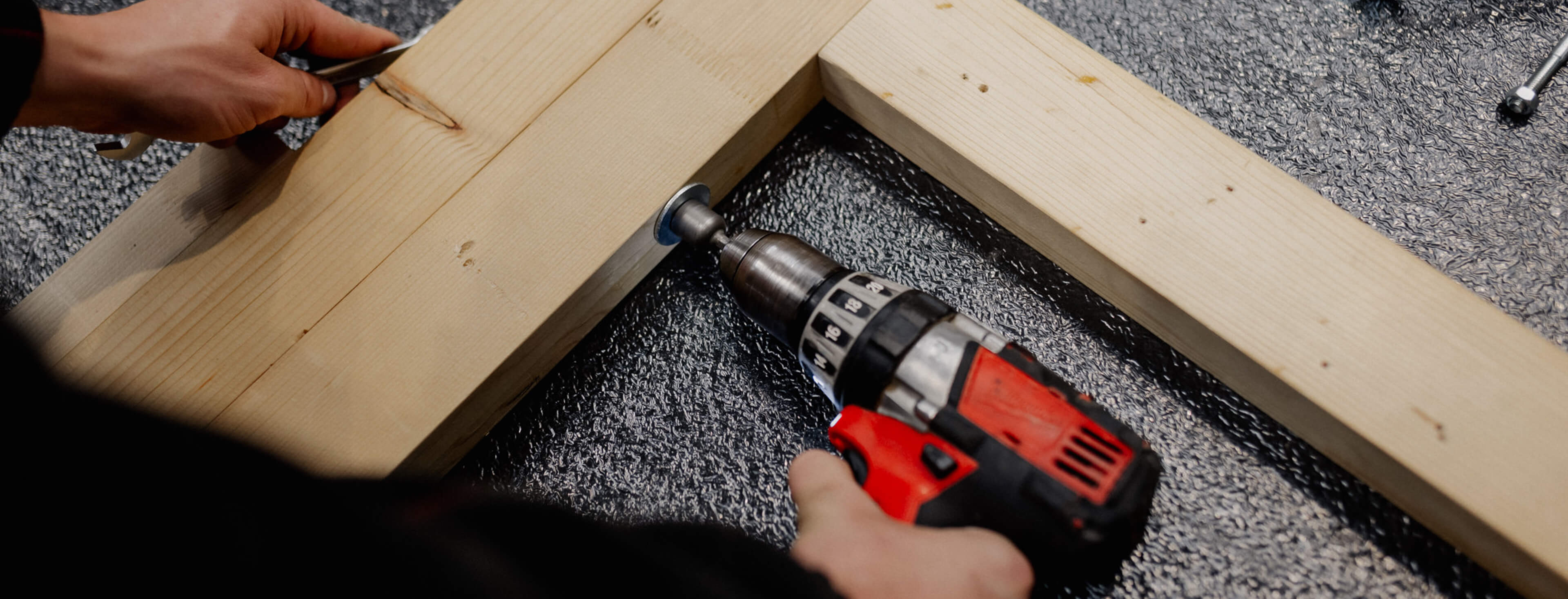 Zaru Handwerker befestigt Holzbalken mit Akkuschrauber bei präziser Arbeit.