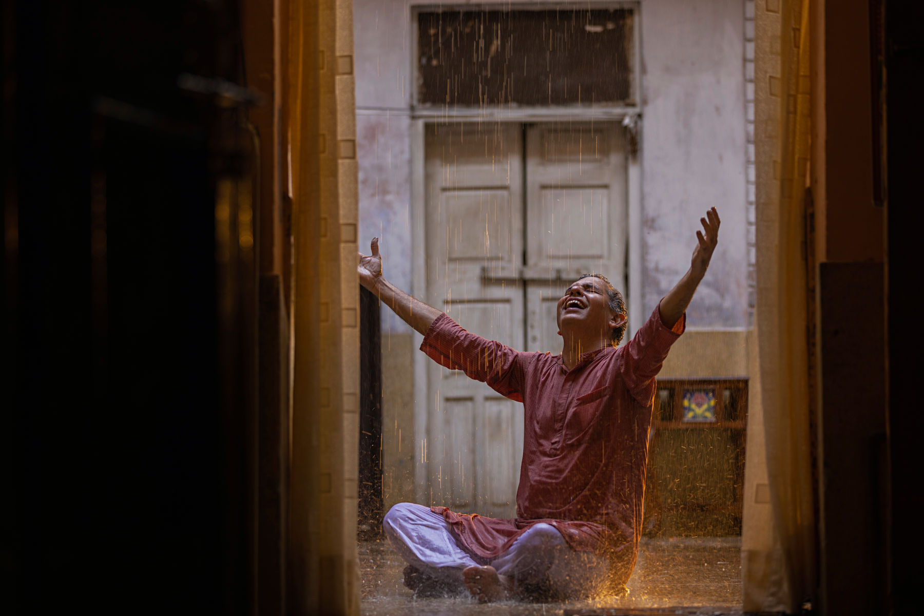 A joyful elderly man relishing the rain symbolises emotional well-being fostered by strength training in India