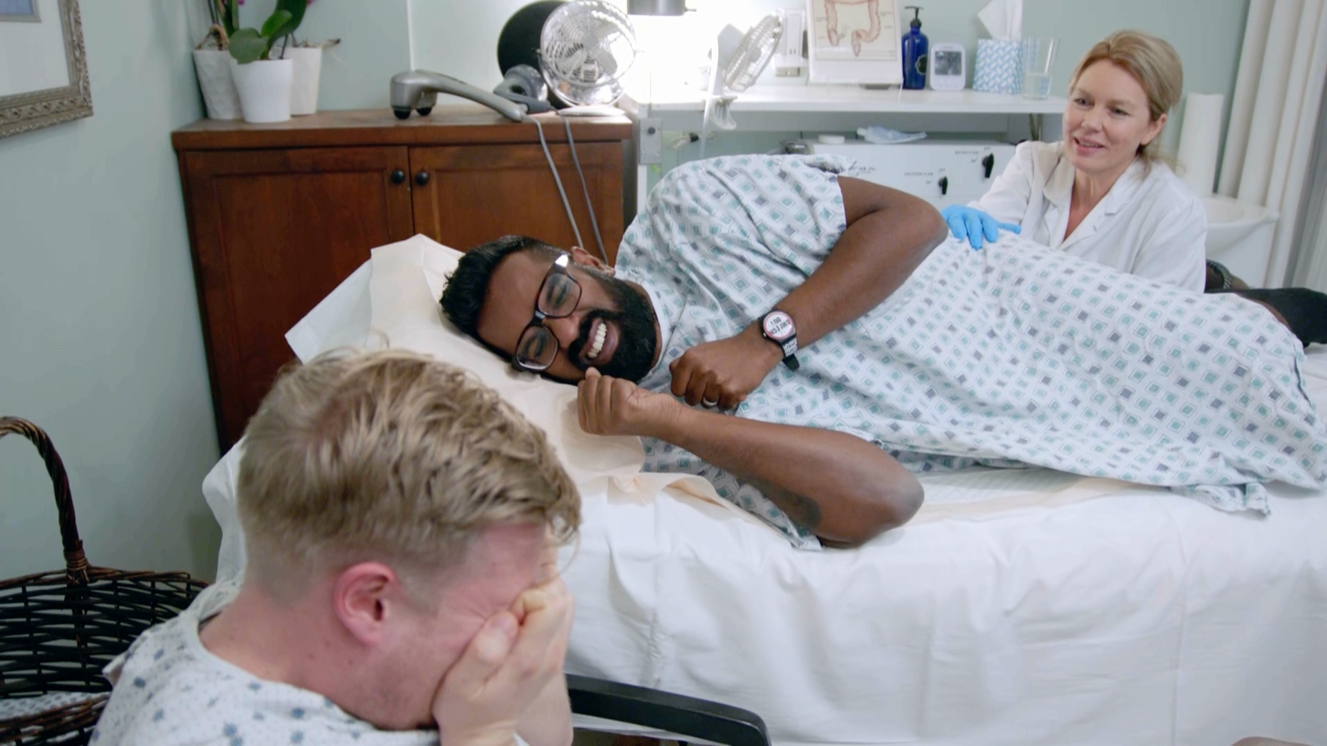 Romesh laughing on a treatment bed while Rob hides his face in his hands, Rob & Romesh Vs NBA