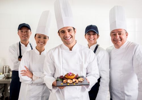 5 chefs one holding a plate of shellfish