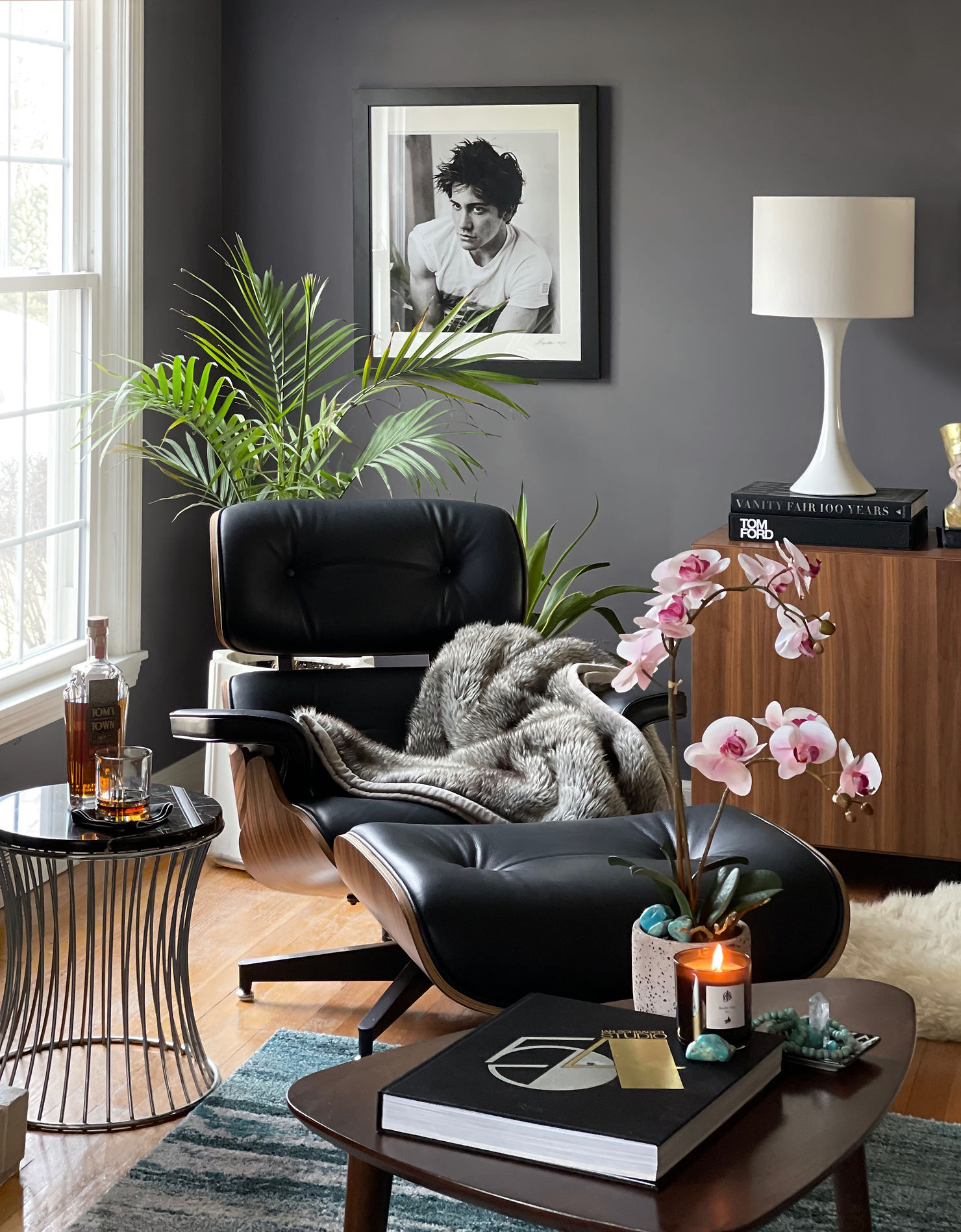 Eames lounge chair positioned beside a fireplace and window in a masculine mid-century living room