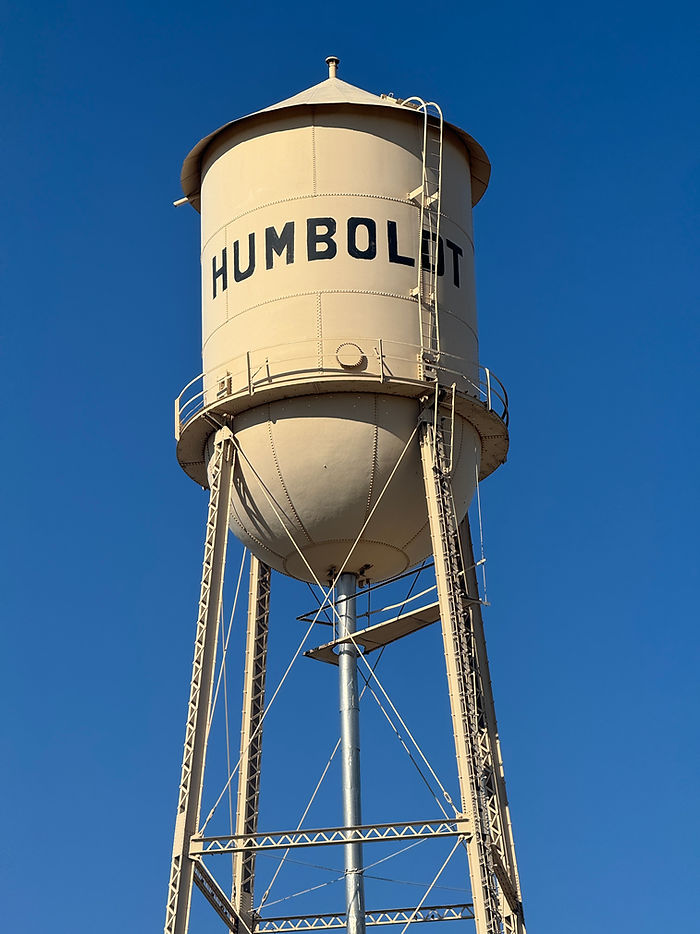 Humboldt water tower rising against a clear blue sky with bold lettering and metal ladder detail