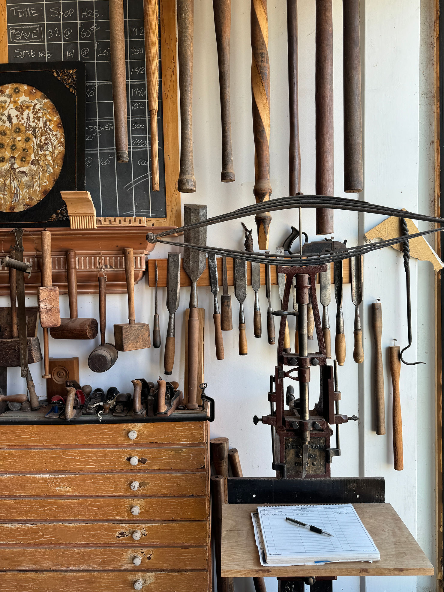 Vintage woodworking tools hanging on a wall in a historic workshop, featuring chisels, mallets, and hand tools with worn wooden handles