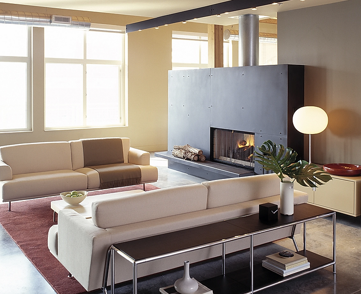 Open-concept loft living room with concrete floors, high ceilings, and warm layered furnishings
