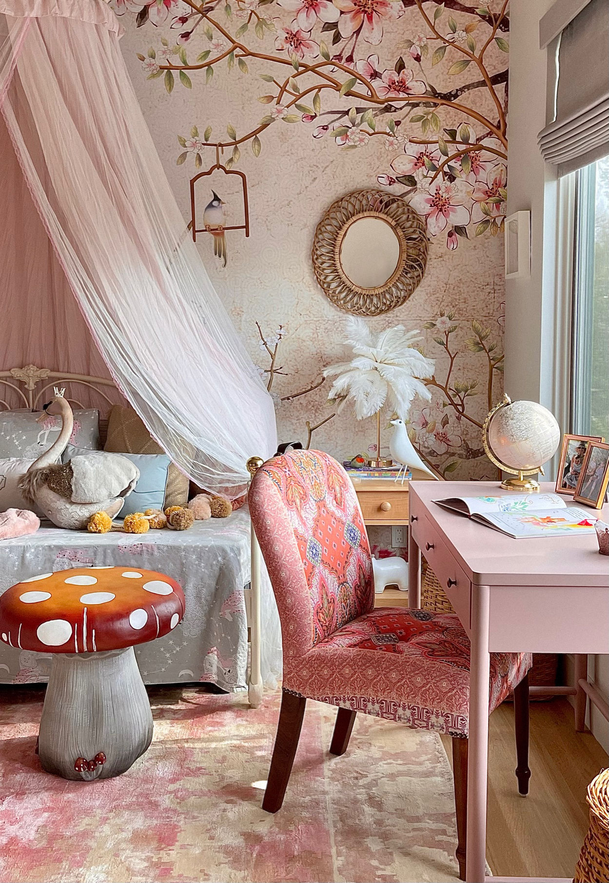 Whimsical children’s bedroom corner with pink desk, patterned chair, mushroom side table, and canopy bed