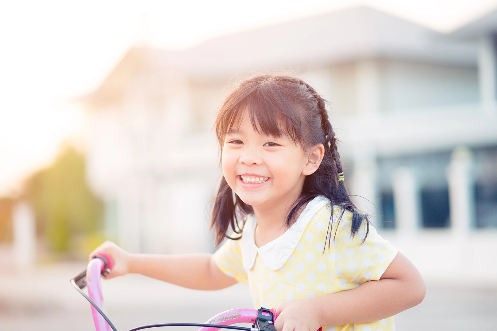 A young child riding her bike, smiling happily