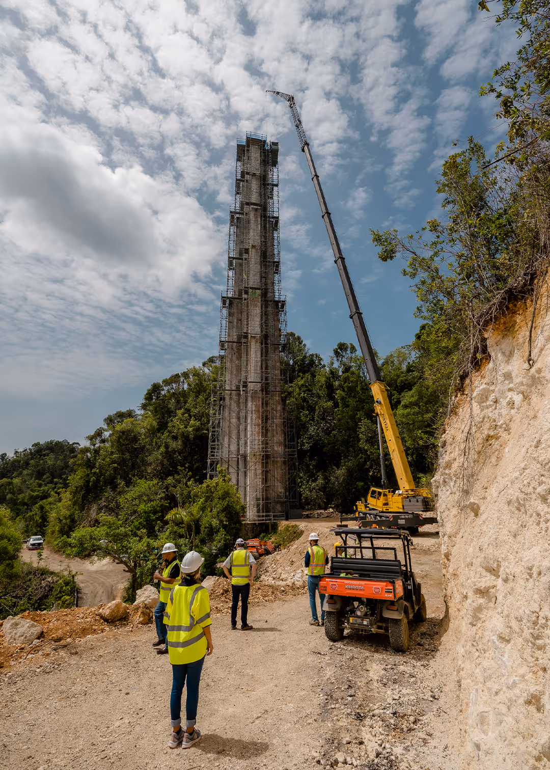 Construction workers overseeing scaffolding tower restoration at Arecibo Observatory in Puerto Rico, with crane and heavy equipment on rugged terrain, highlighting advanced construction safety and infrastructure support.