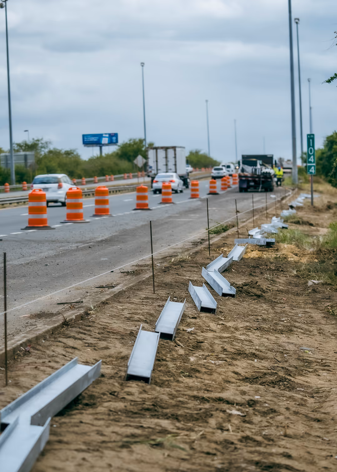 Highway construction project in Puerto Rico with traffic cones, vehicles, and guardrail installation in progress along roadside.