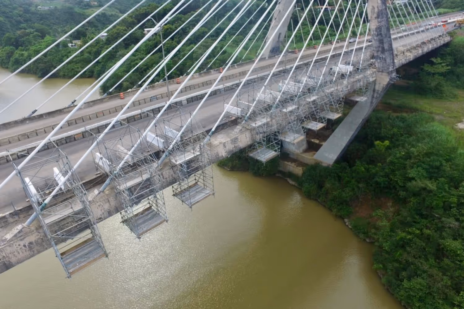 Scaffolding and suspended access platforms under bridge construction in Puerto Rico, representing the 1988 launch of Ace Forming Systems and expansion into scaffolding, formwork, and advanced access solutions.