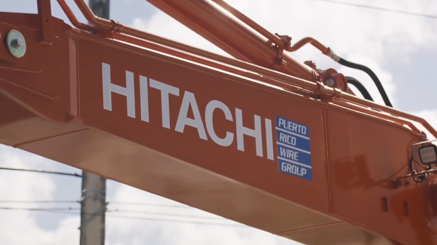 Hitachi excavator displaying Puerto Rico Wire Group branding at a construction jobsite in Puerto Rico.