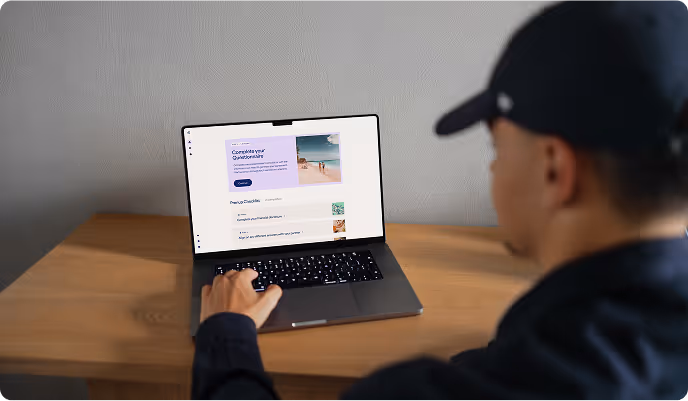Person in a dark cap using a laptop on a wooden desk, with a webpage open showing a questionnaire and images.