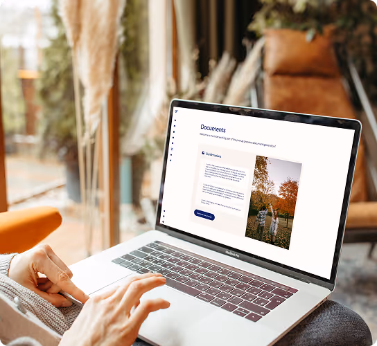 Person using a laptop on their lap displaying a document management interface with text and a photo of two people with autumn trees.