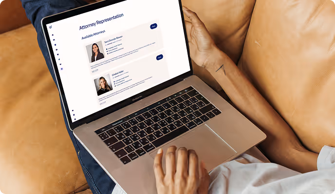 Person holding a laptop on their lap showing a webpage titled 'Attorney Representation' with profiles of two available attorneys.