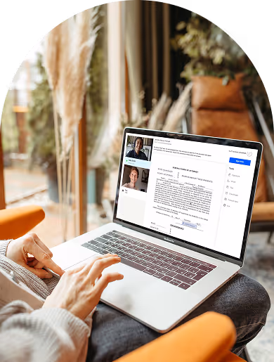 Person using a laptop showing an online notarization video call with two people and a document on the screen.