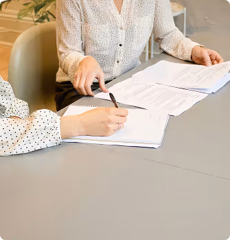 Two people reviewing and signing documents at a table.