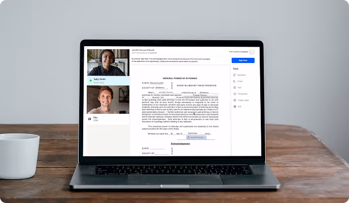 Laptop on wooden table displaying a digital document signing interface with profile photos and sign options.