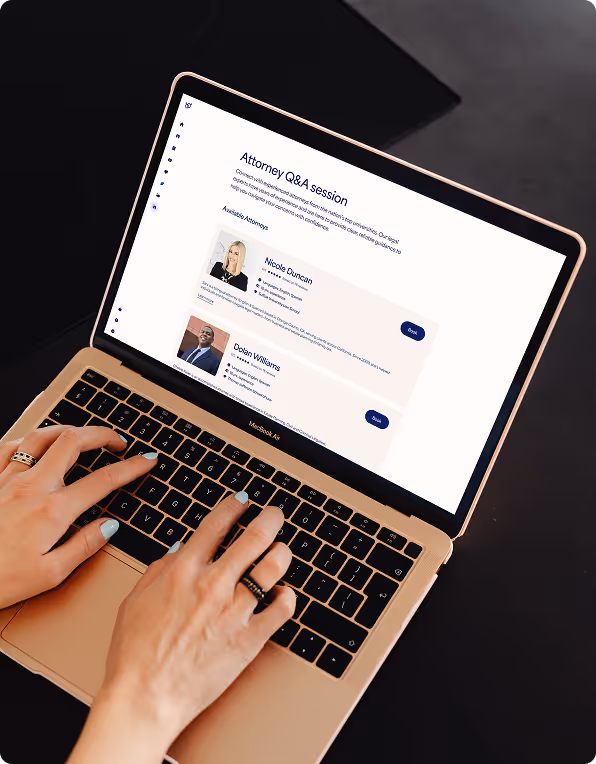 Person typing on a MacBook Air displaying an Attorney Q&A session webpage with profiles of two attorneys and a chat button.