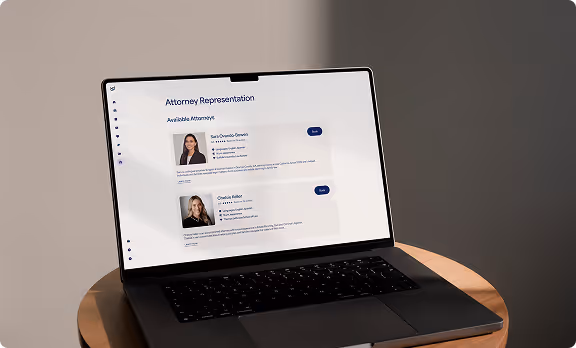 Laptop on round wooden table displaying a webpage titled 'Attorney Representation' listing two attorneys with photos, names, and contact buttons.