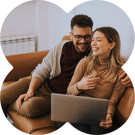 Smiling young couple sitting on a couch using a laptop together.
