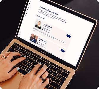 Person typing on a MacBook Air displaying an Attorney Q&A session webpage with profiles of two attorneys.