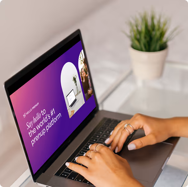 Hands typing on a laptop keyboard showing a screen with text 'Say hello to the world's #1 prenup platform' on a purple background with small images of a laptop and a smiling woman.