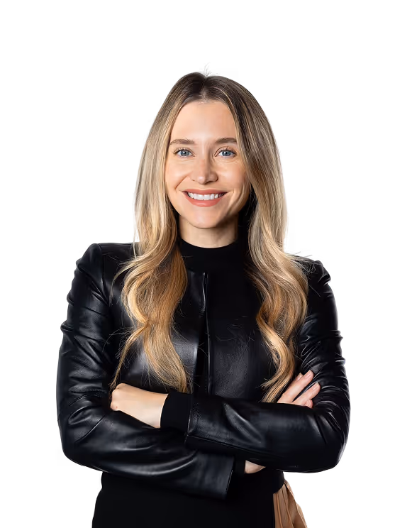 Smiling woman with long blonde hair wearing a black leather jacket with arms crossed.