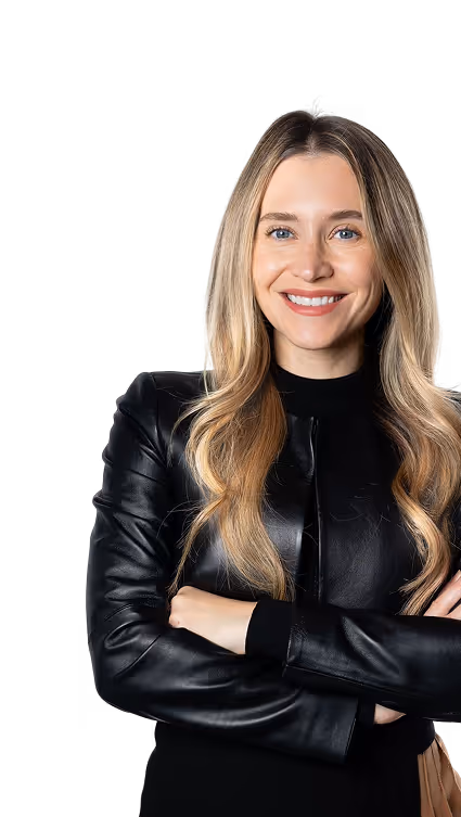 Smiling woman with long blonde hair wearing a black leather jacket and crossing her arms.