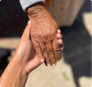 Younger hand gently holding an older, wrinkled hand in a comforting gesture.