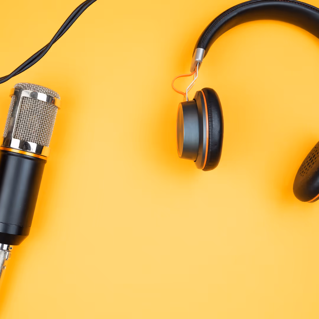 Black and orange headphones and a studio microphone on a yellow background.