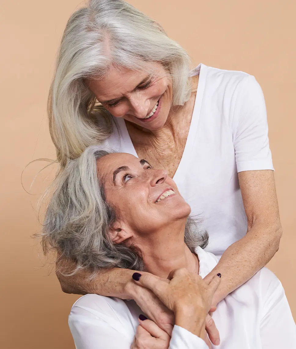 Two women wearing white embracing.