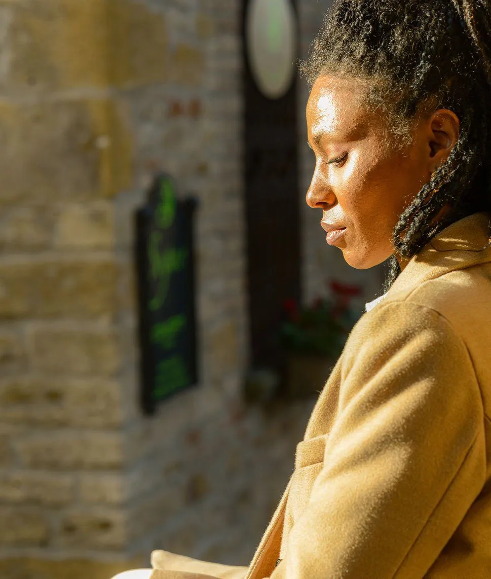 Woman looking down while walking along a sunny street.