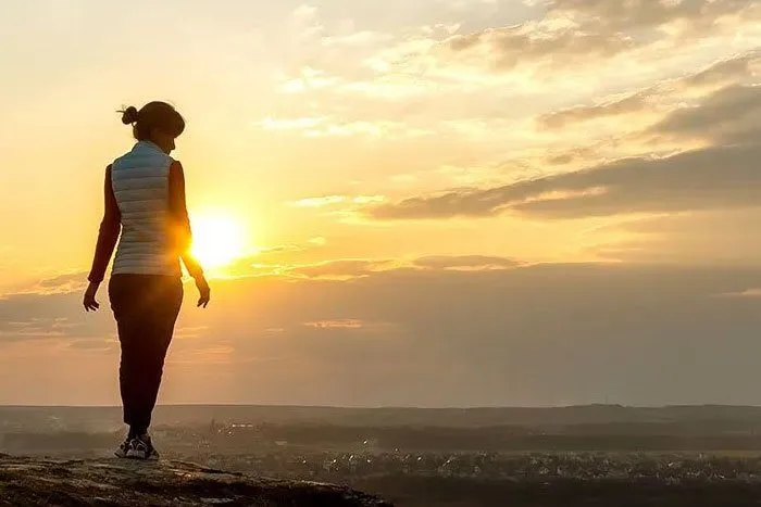 Woman standing on mountain at sunrise.