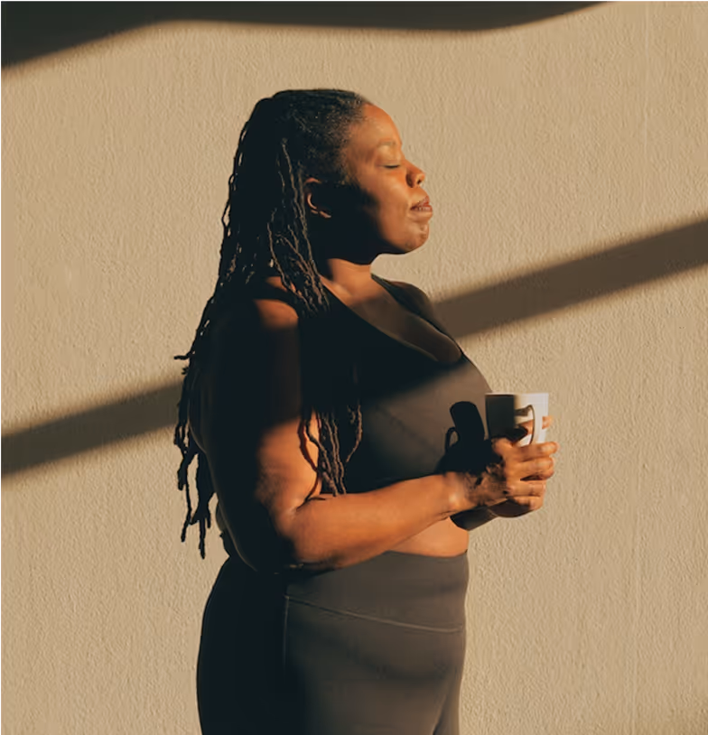 woman standing by the window enjoying sunlight