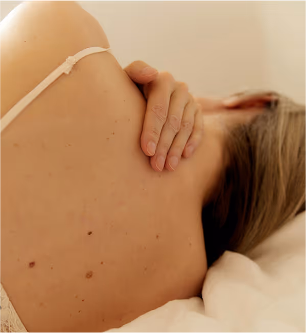 Women lying in bed massaging neck.