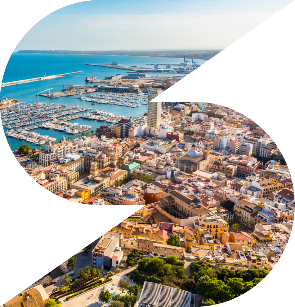 Aerial view of a coastal city with a marina full of boats and dense urban buildings near the blue sea.