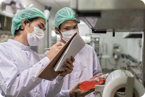 Food safety technicians reviewing production checks on paper inside a processing facility, illustrating the manual documentation challenges that digital QMS onboarding replaces with faster, organised and fully visible workflows.