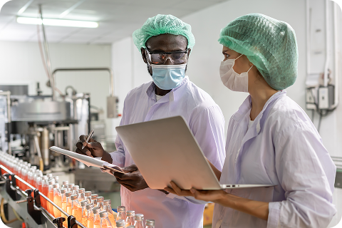 Food production staff reviewing quality checks on a beverage line, using a mix of paper and digital tools, highlighting the challenges of manual workflows in food safety and compliance.