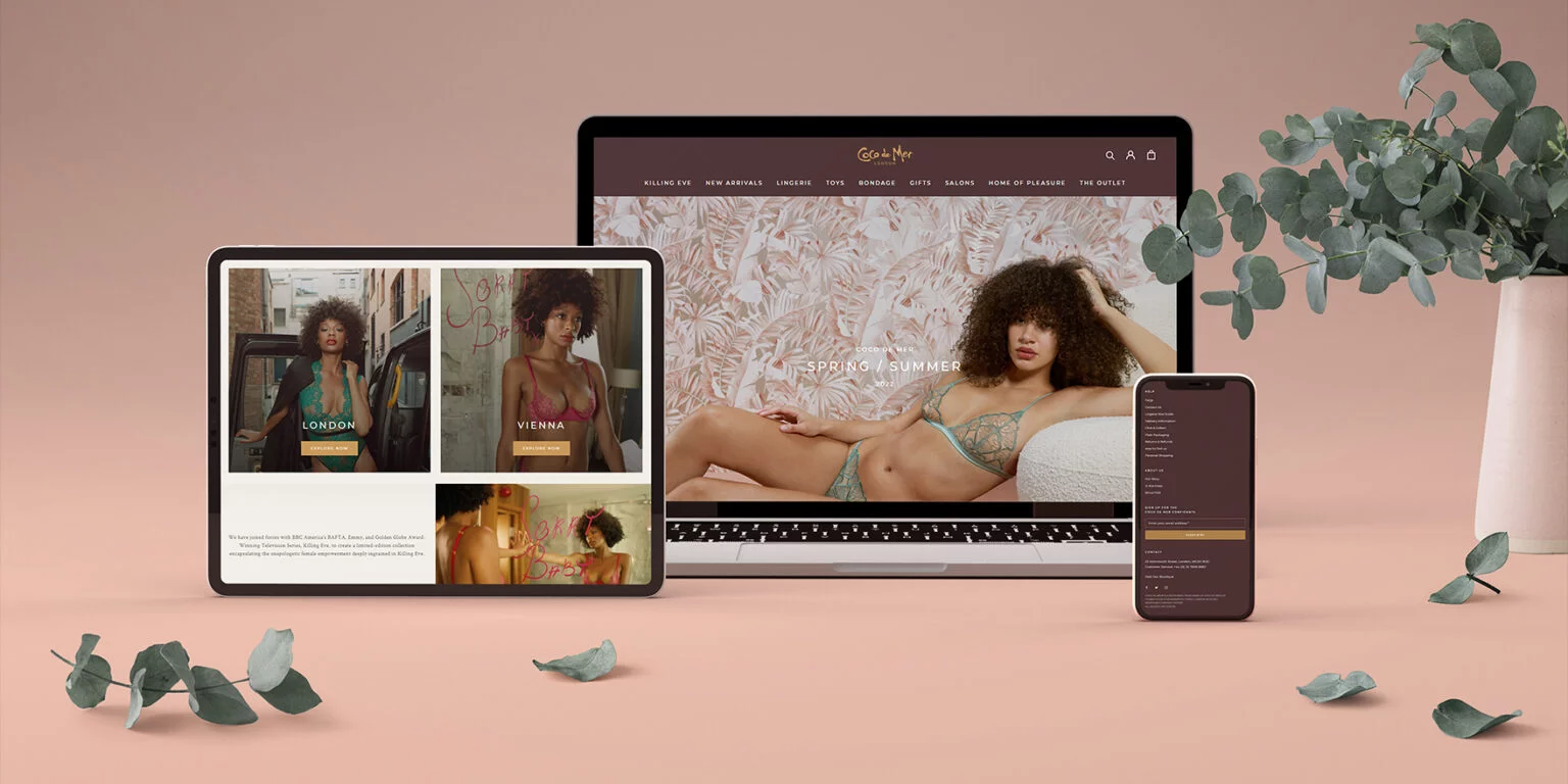 Three devices—a tablet, laptop, and smartphone—displaying a lingerie website featuring a model in lace lingerie and homepage navigation, set against a soft pink background with eucalyptus leaves and a vase.