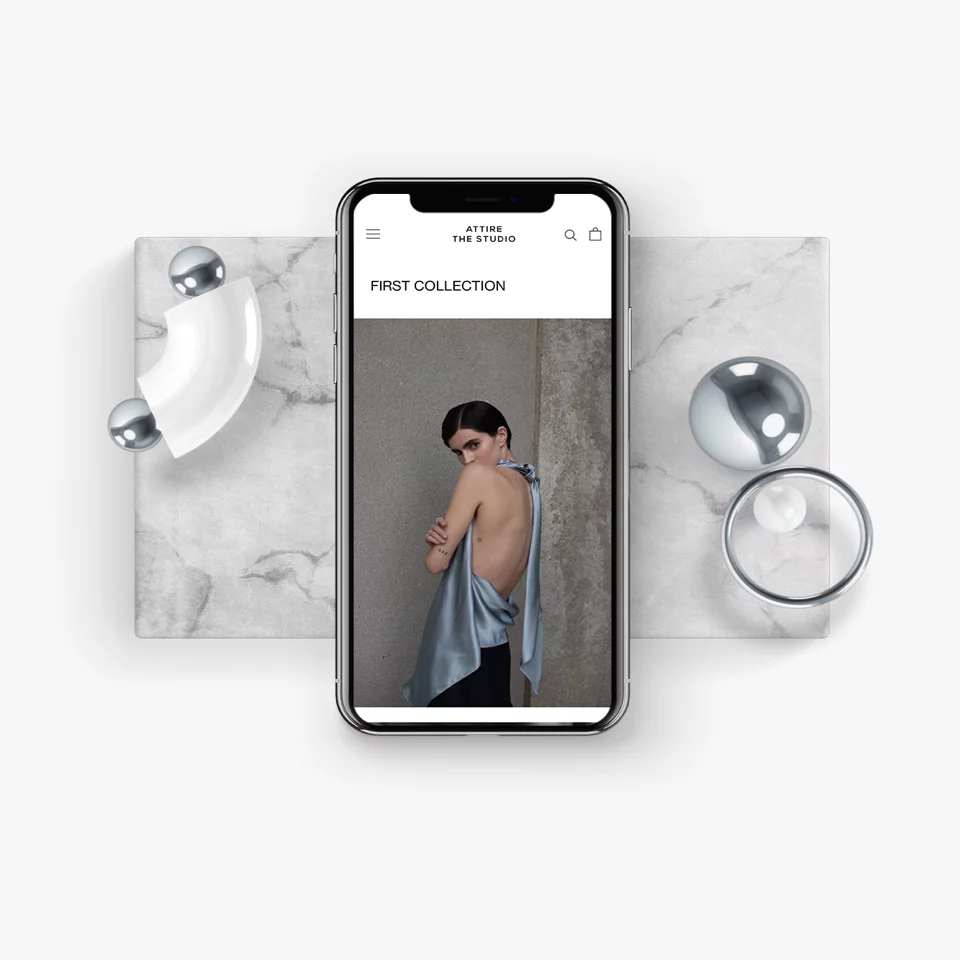 Smartphone displaying a fashion website with a backless blue satin top worn by a model against a neutral background.