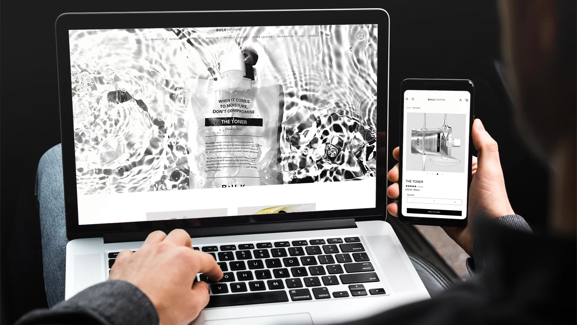Person using a laptop and holding a phone displaying BULK HOMME skincare product page for THE TONER.