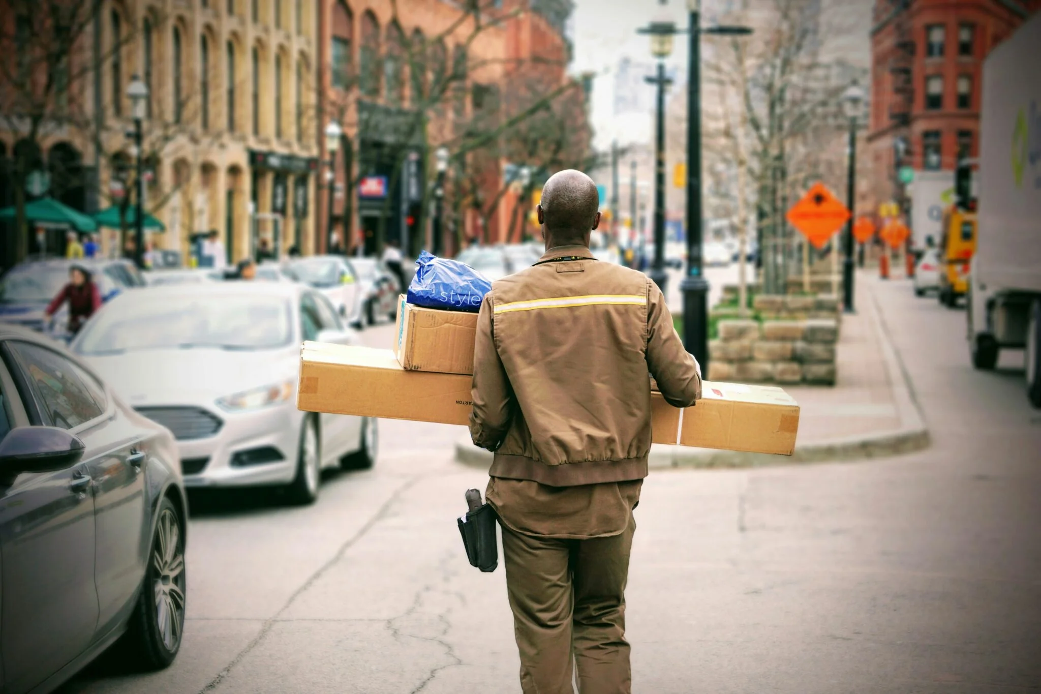 Courier in a brown uniform carrying parcels down a city street, illustrating international shipping and foreign returns