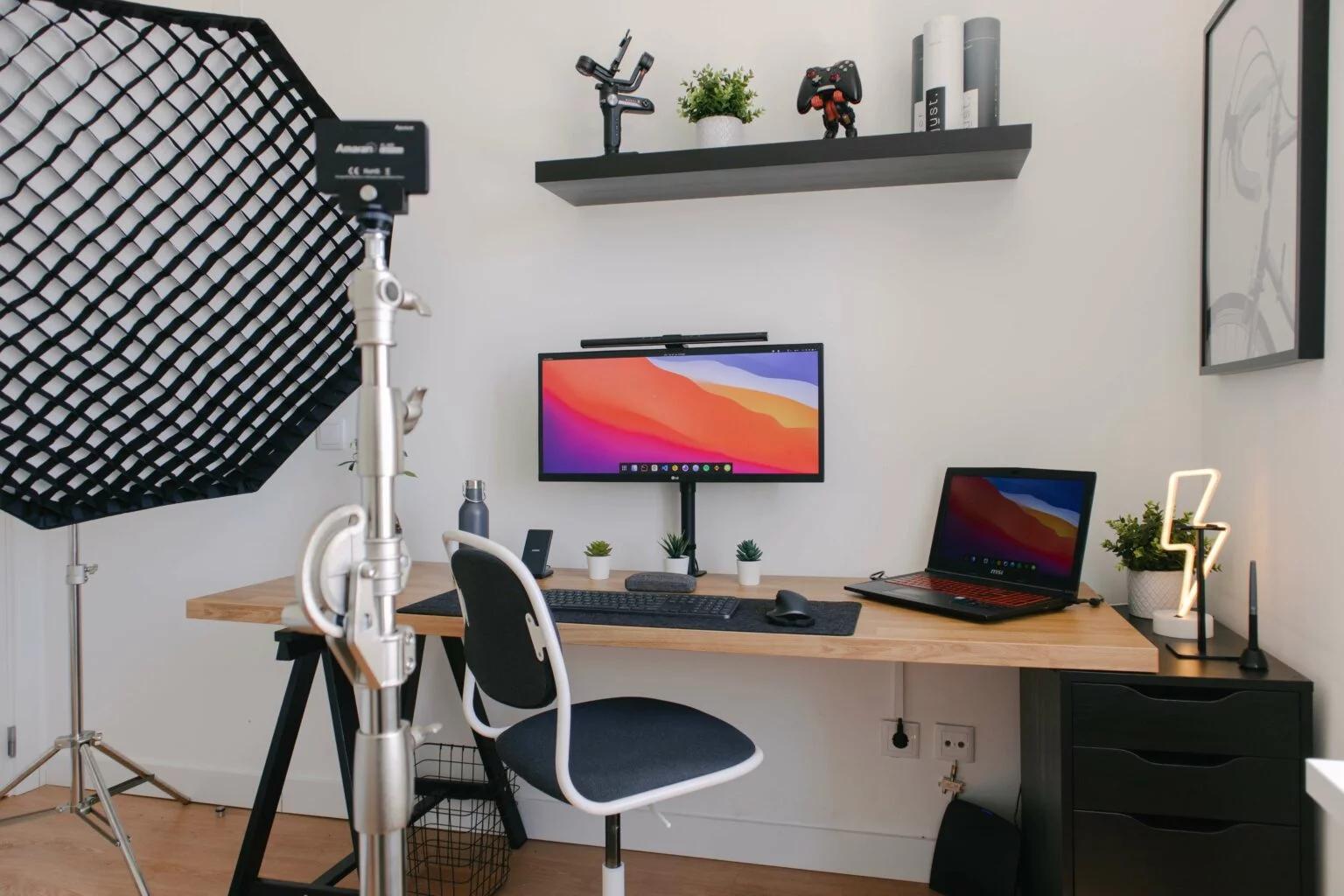 Home office desk with monitor, laptop, keyboard and a studio softbox light, a workspace for running a Shopify Plus store