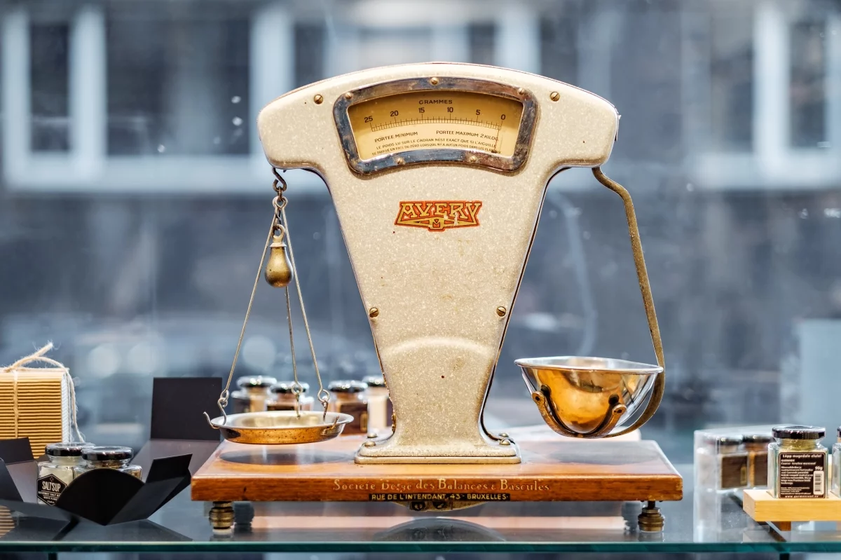 Vintage Avery balance scale with brass pans in a shop window, symbolising weighing Shopify Advanced against Shopify Plus