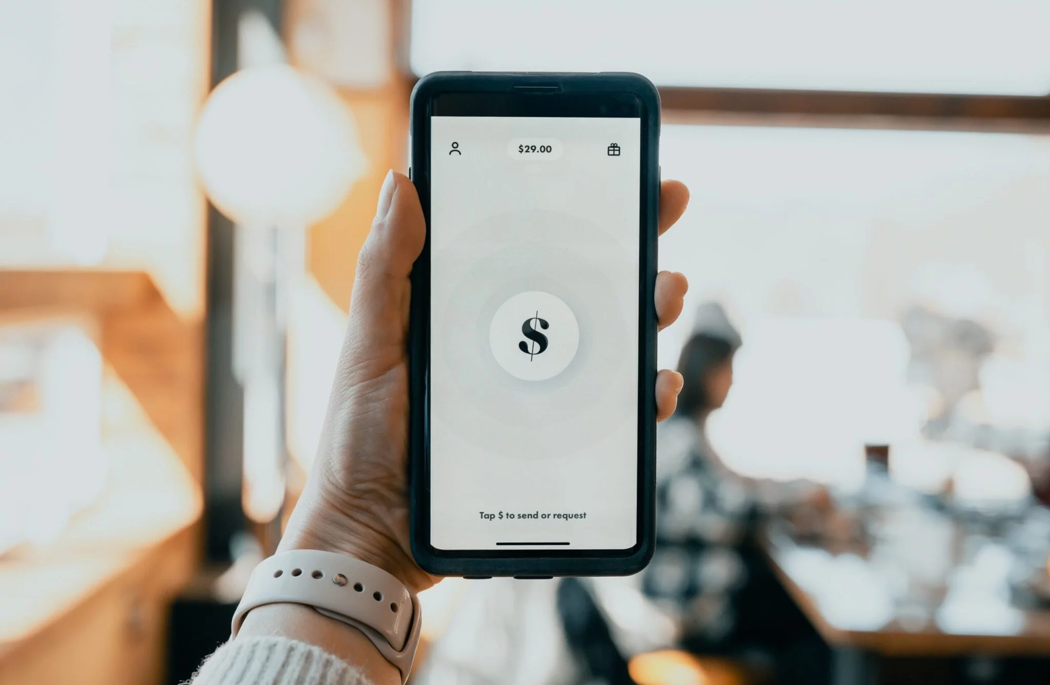 Hand holding a smartphone with a payment app showing $29.00, illustrating the costs of running a Shopify store