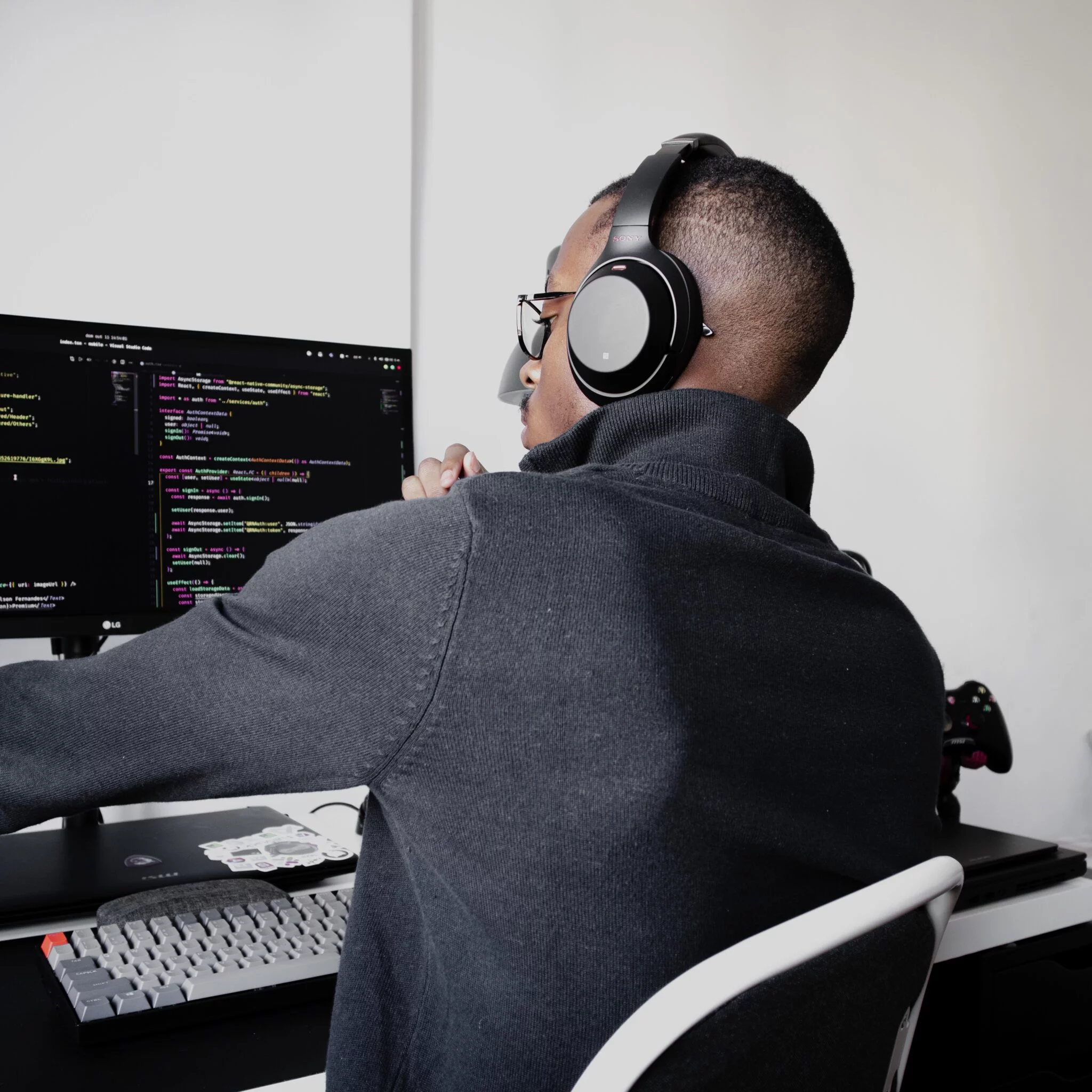 Developer in headphones writing code on a large monitor, illustrating building a headless storefront with Shopify Hydrogen
