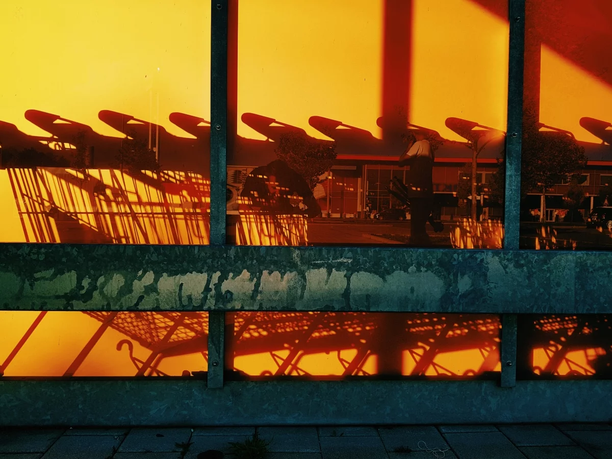Silhouettes of shopping carts reflected on an orange glass wall outside a store, alluding to cart abandonment
