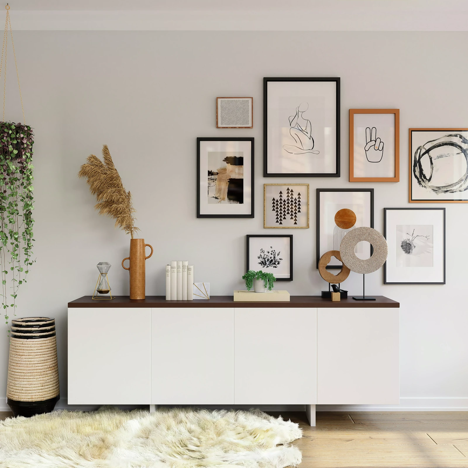 White sideboard with vases, books and dried grass below a gallery wall of framed art prints, inspiring home decor