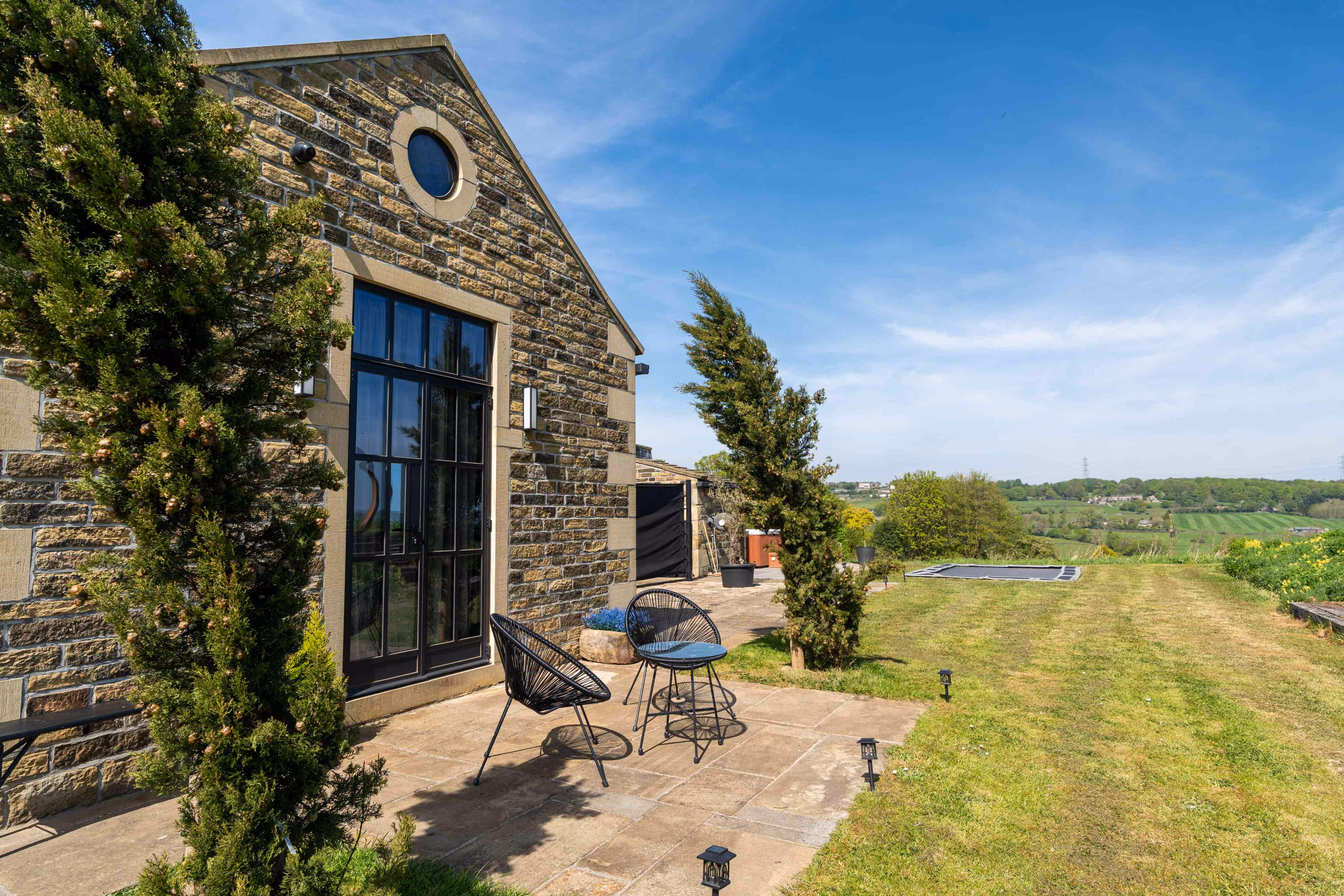 a wide shot of the exterior of the annex. showing the green grass and the woodland in the far distance.