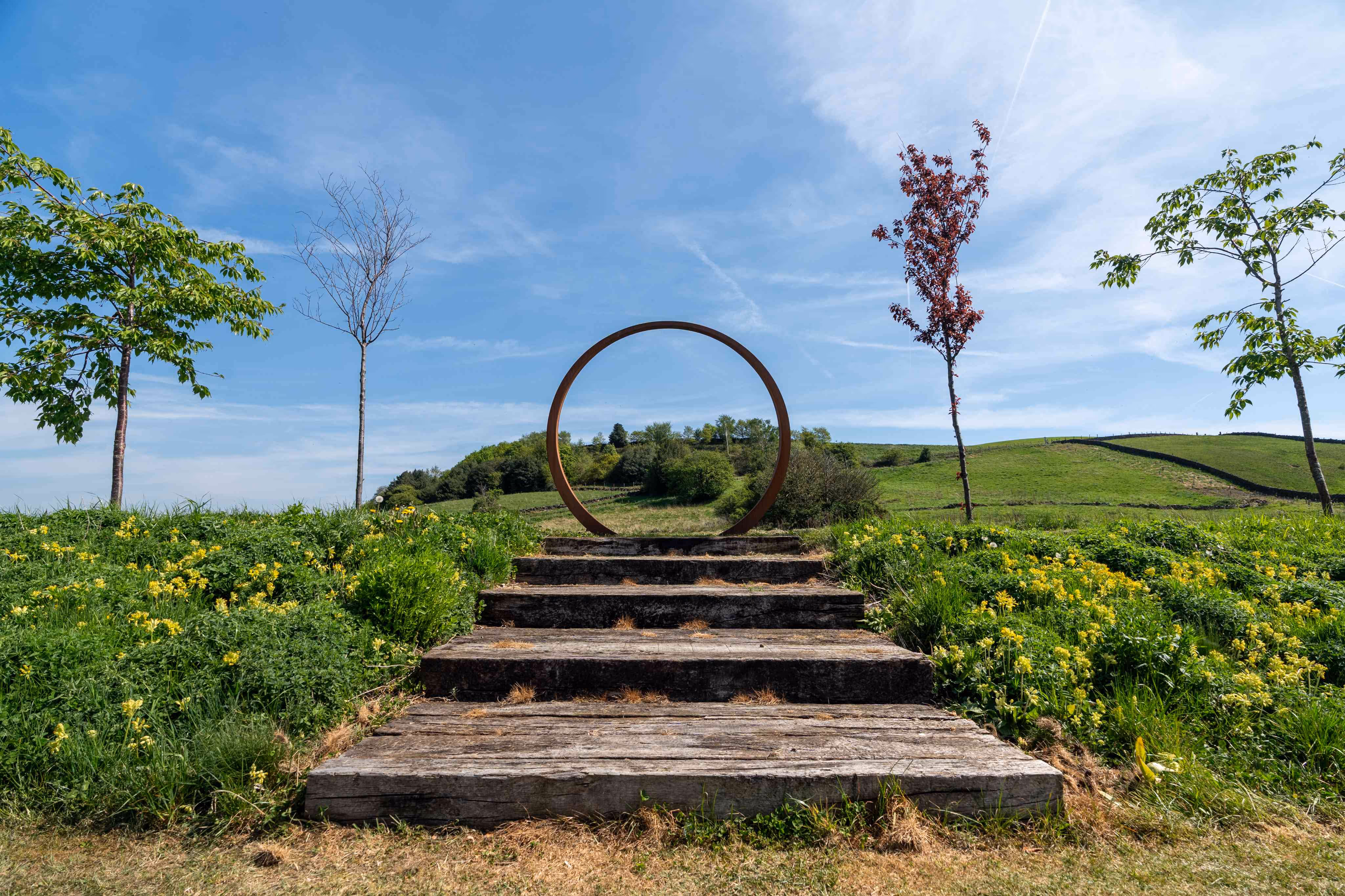 Steps leading to a circular arch frames the woodland in the distance