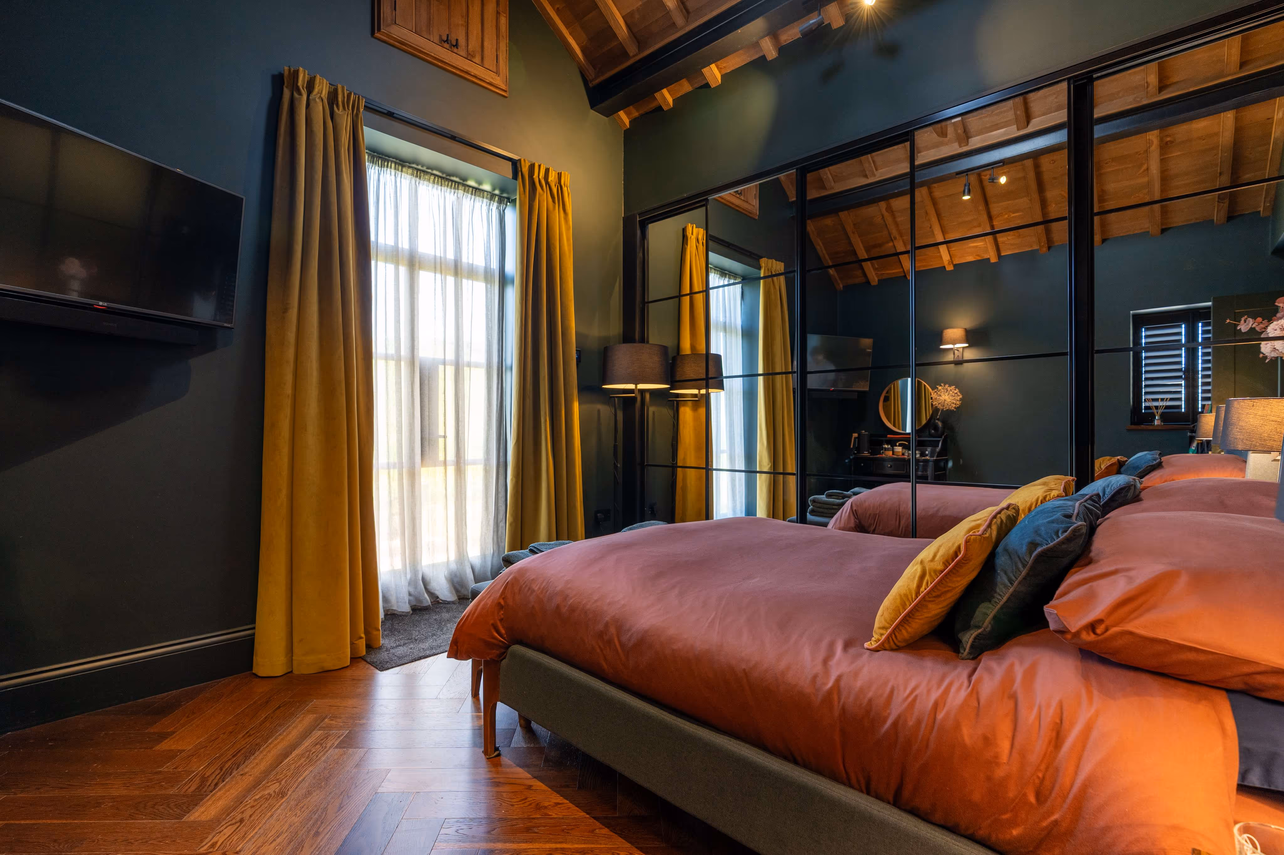 The annex bed show the space around it enhanced by a wall of mirrored wardrobes which bounces light around the space.